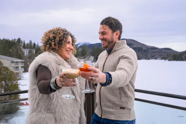 Two people raising their drinks on a wintery patio.