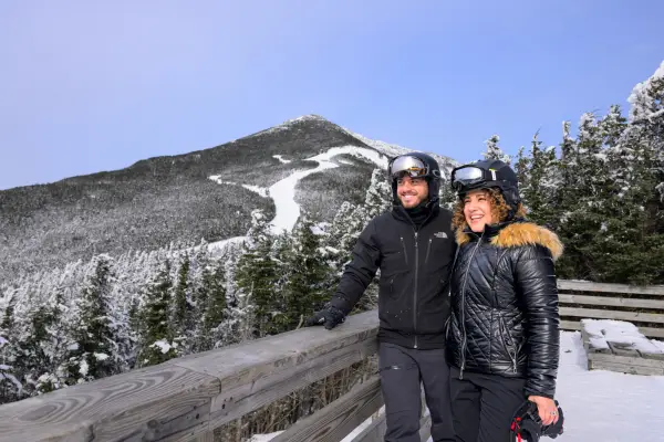 A couple posing for a photo in front of Whiteface Mountain.