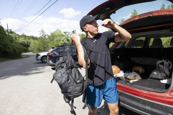 A hiker at the back of his car with his backpack