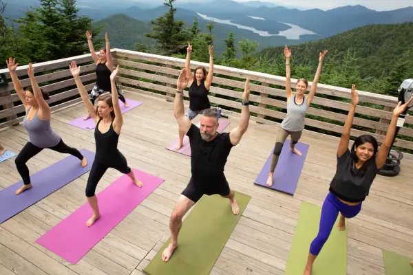 People doing yoga outside on a deck.