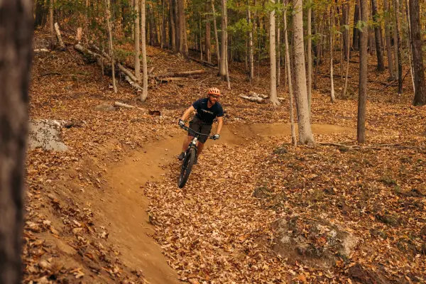A mountain biker going around a berm in the fall.