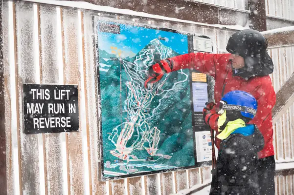A skier points to the mountains trail map