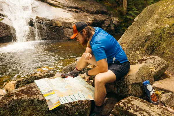 Ah iker looks at a map by a waterfall