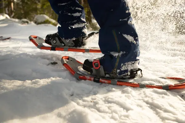 A close up photo of person snowshoeing through a snowy trail.