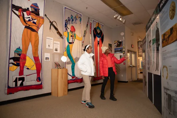 Two women in white and red jackets explore an Olympic museum. 