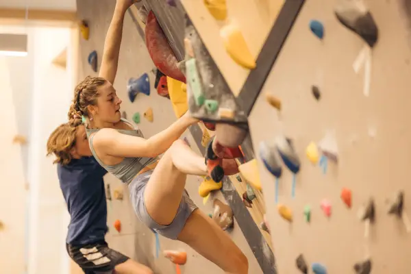 A woman rock climbs in a rock climbing gym. 