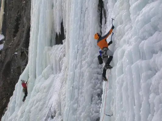 A person ice climbing up an icy rock ledge.