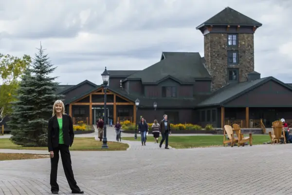 A woman poses with a college in the background. 