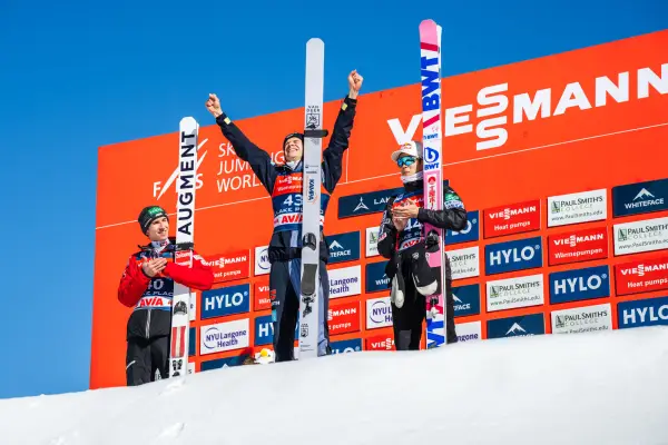 Three skiers accept their awards on a snowy podium. 