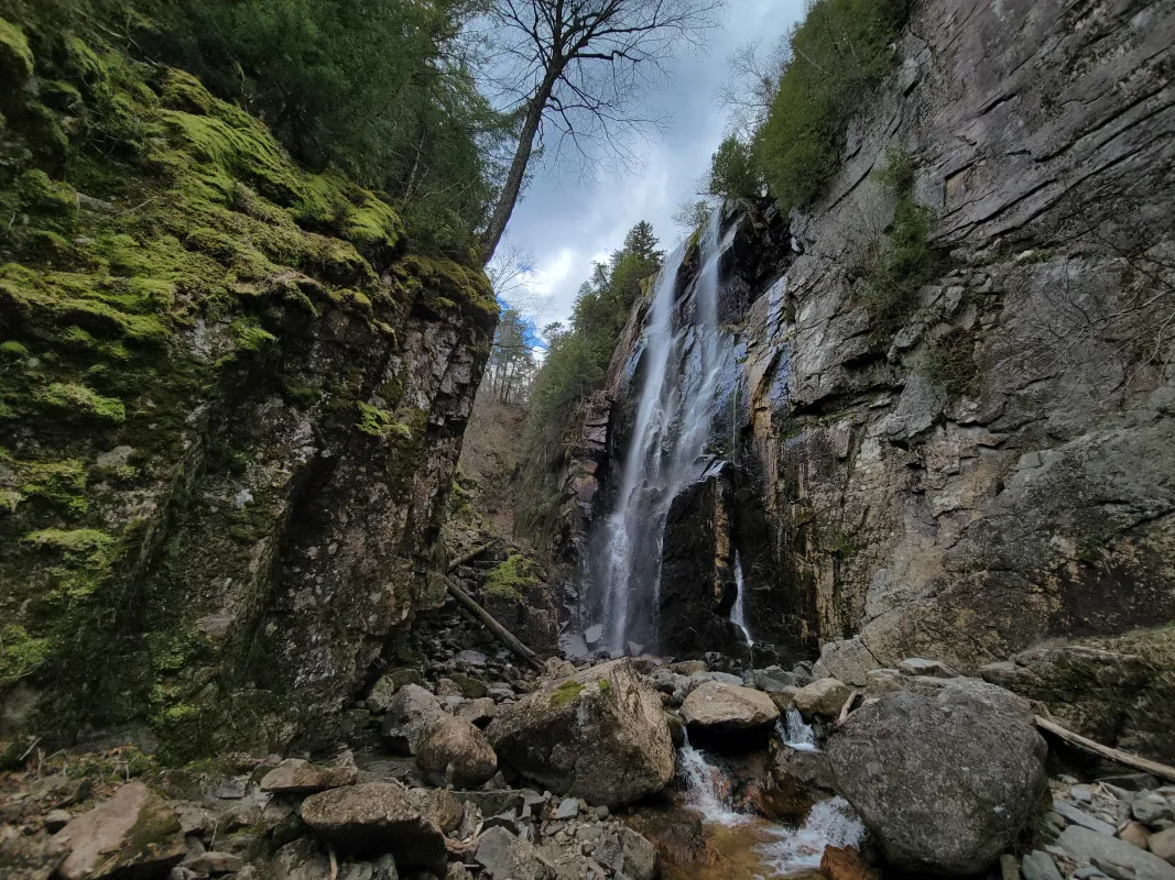 A tall waterfall in a narrow, mossy canyon.