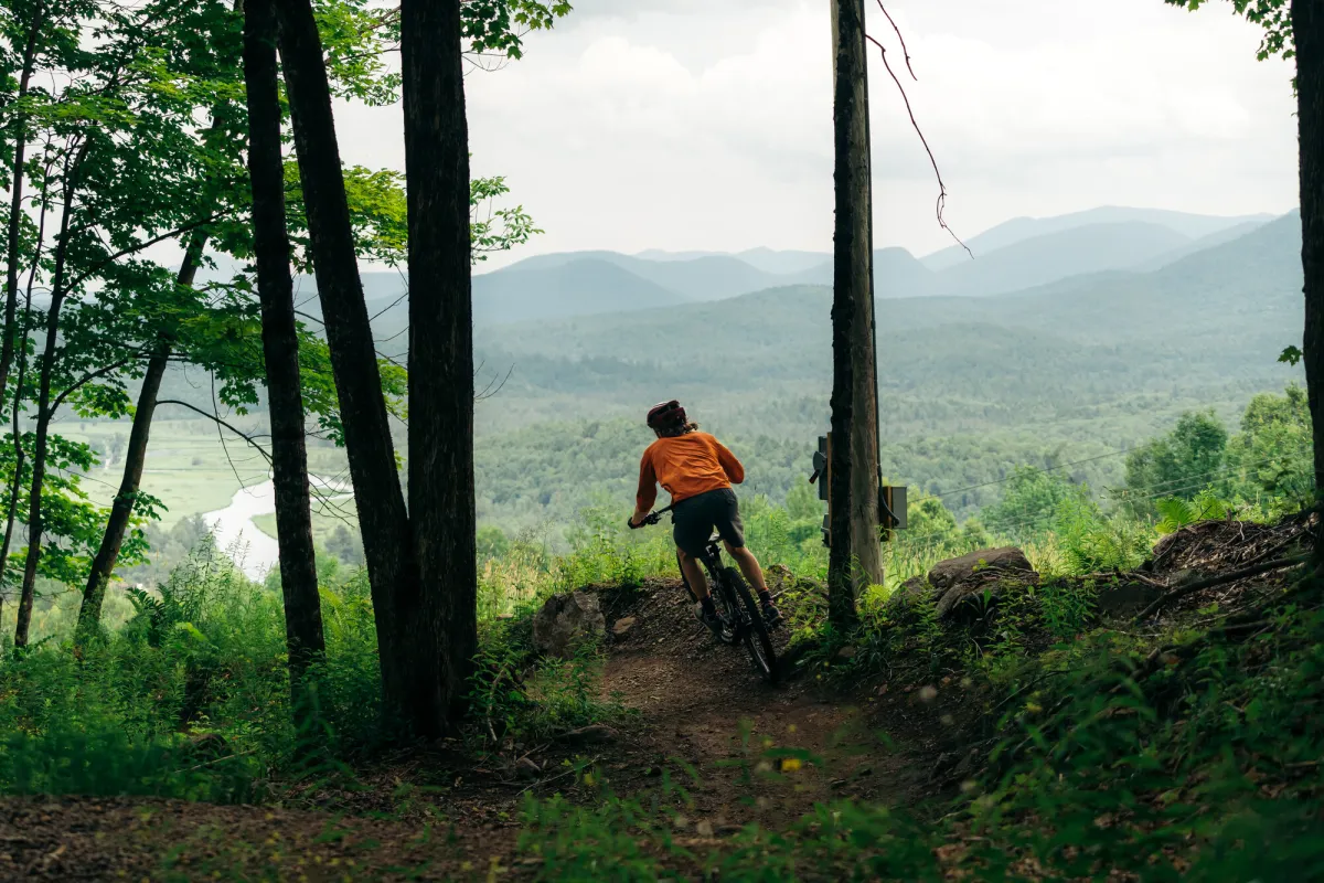 A person mountain biking down a trail during the summer.