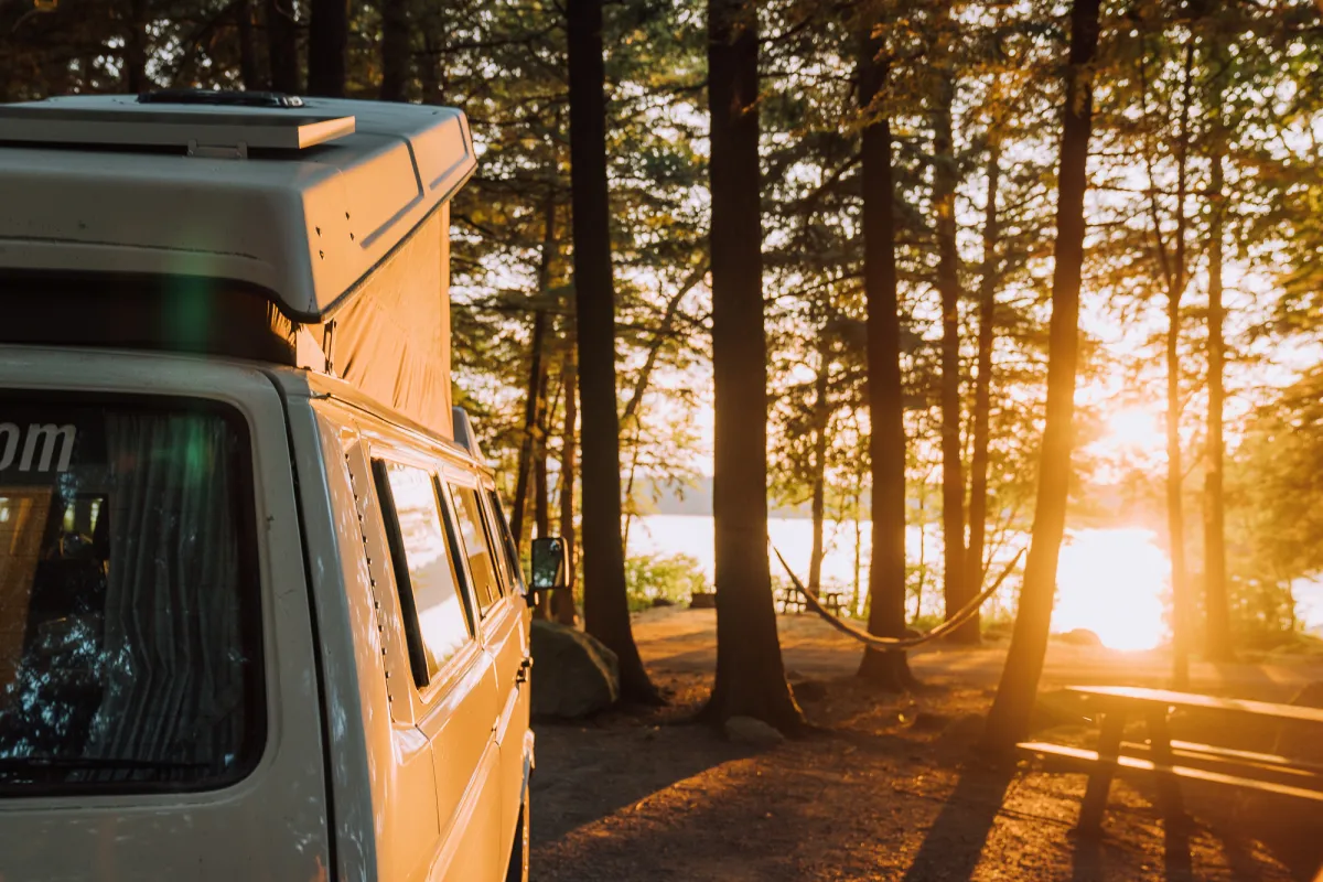 A camper van parked at a campground at sunset.