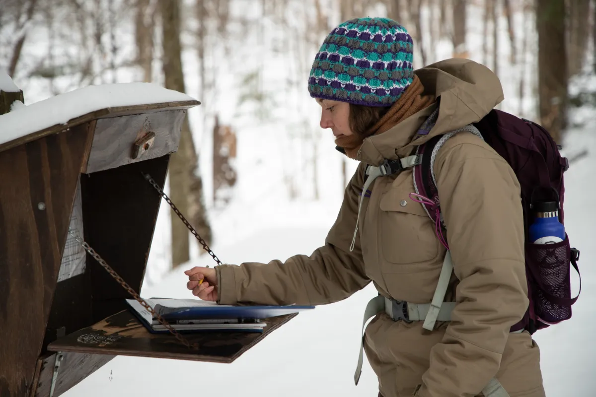 A woman signing into a trail register in the winter