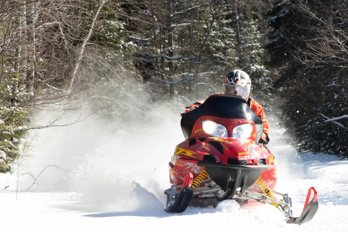 A snowmobiler riding through a snowy trail.