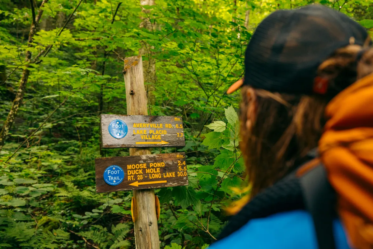 A hiker looks at a trail sign