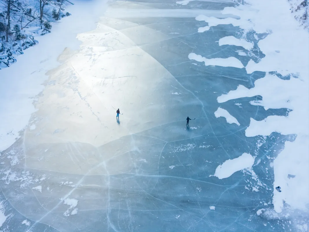 Two ice skaters on a frozen lake.