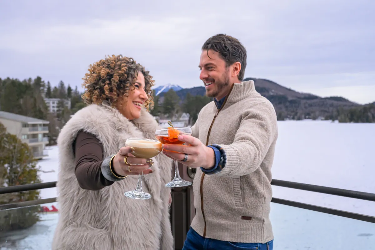 Two people raising their drinks on a wintery patio.
