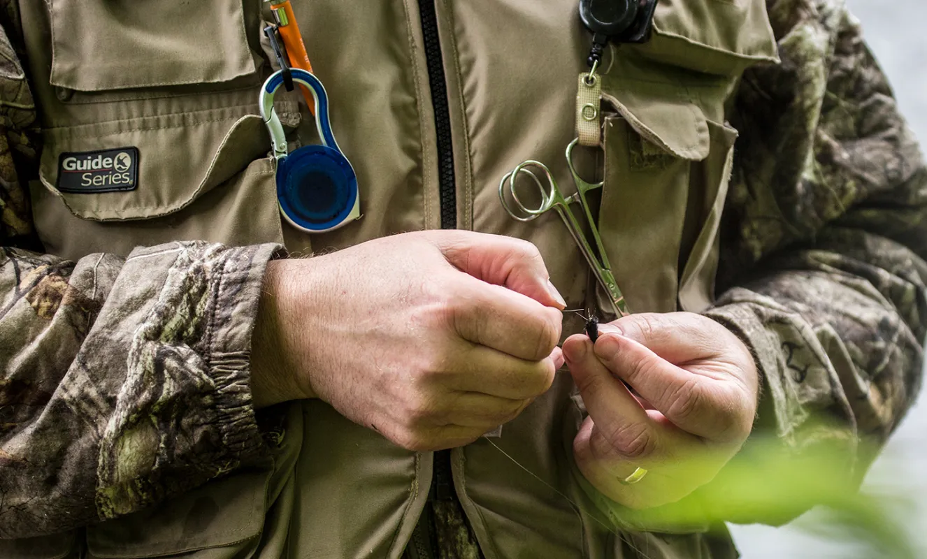 A fisherman ties his fly on.