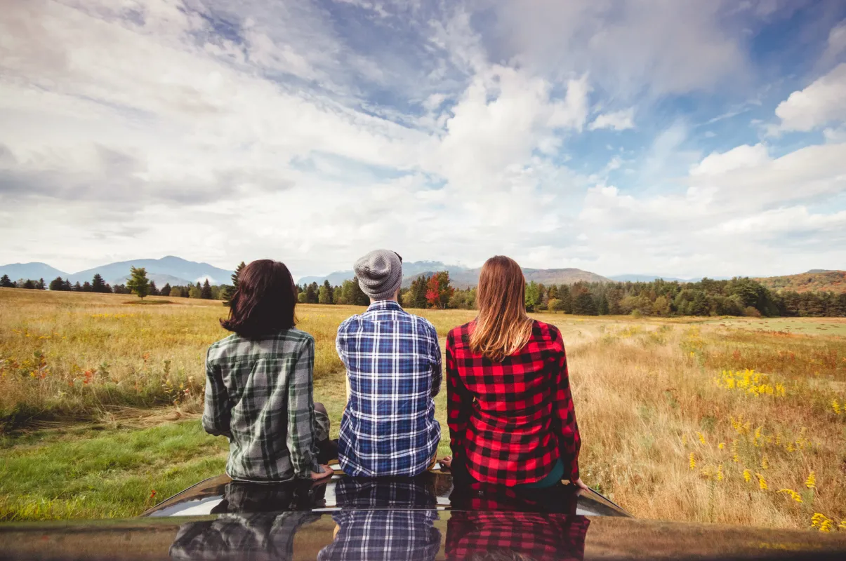 Three people sit on hood of car