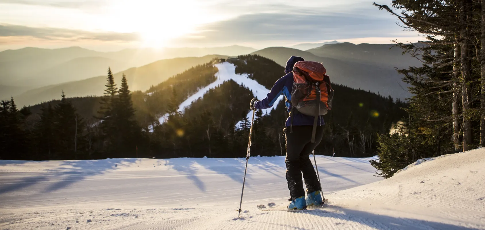 An uphill skier at Whiteface Mountain, looking out to a sunrise.
