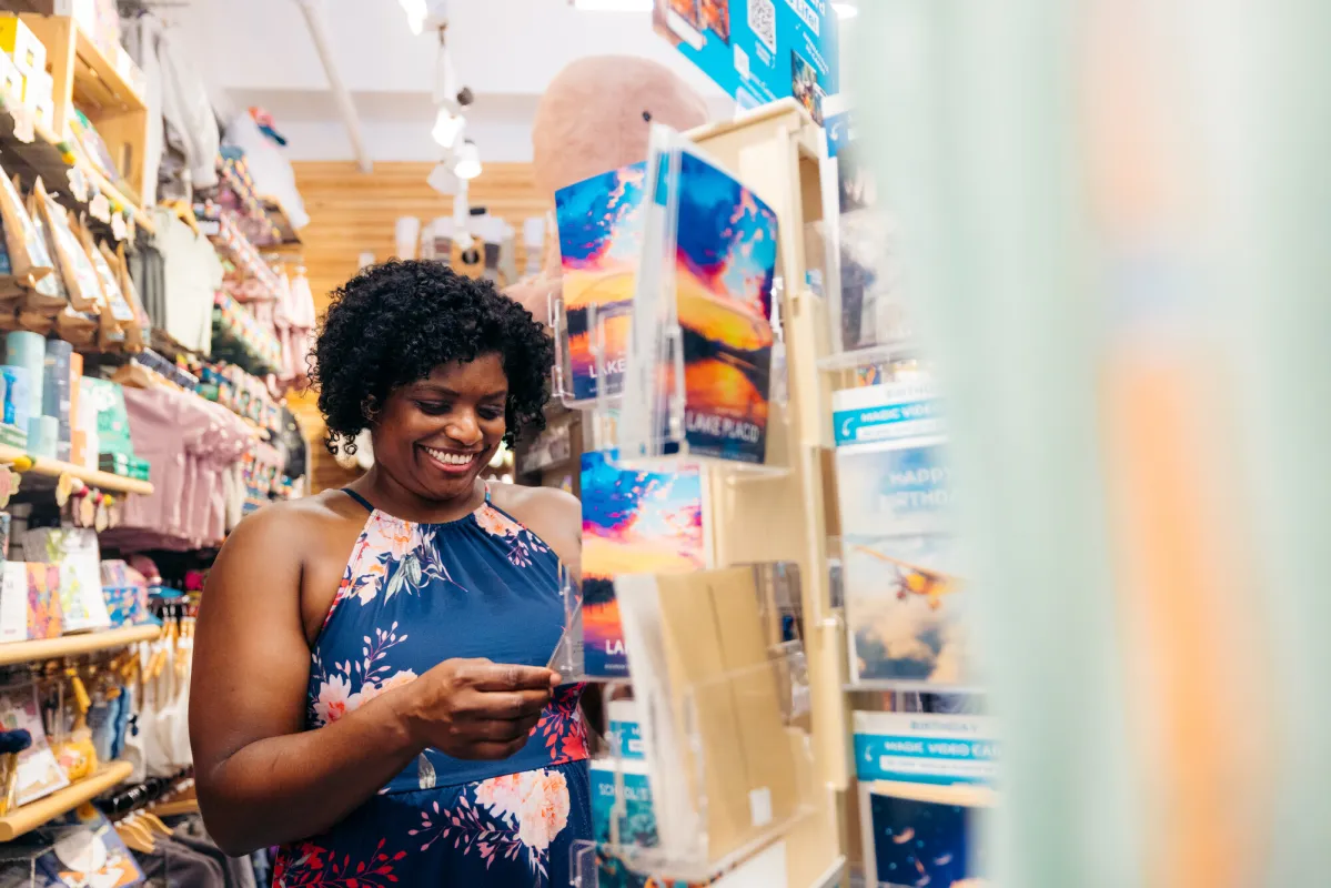 A woman smiles while shopping in a brightly-colored gift shop.