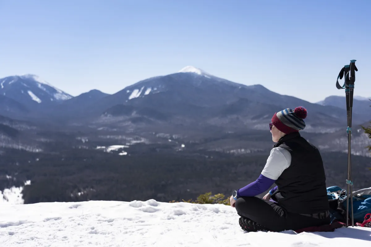 A hiker sitting at the summit of Mt Van Hoevenberg in the winter