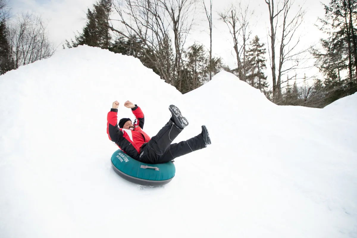 A man rides a tube down a snowy hill. 
