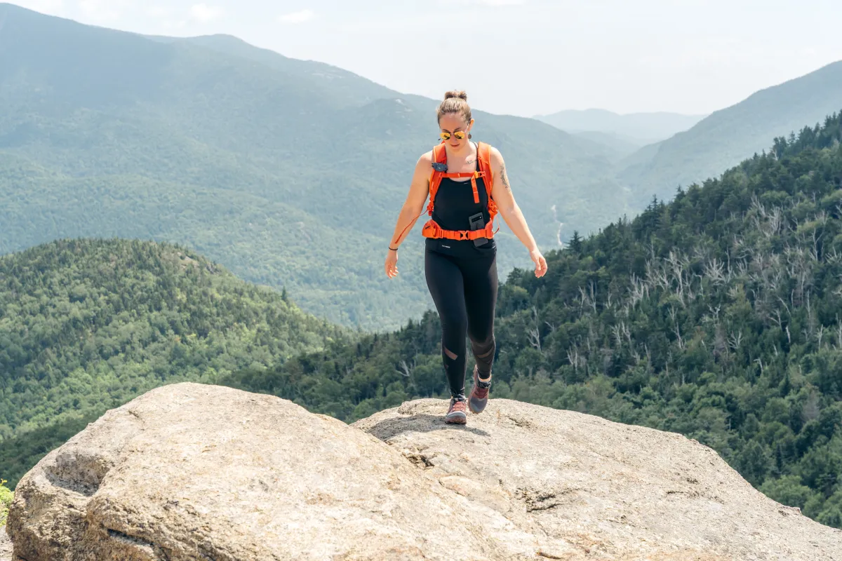 A woman walks on a mountain top.
