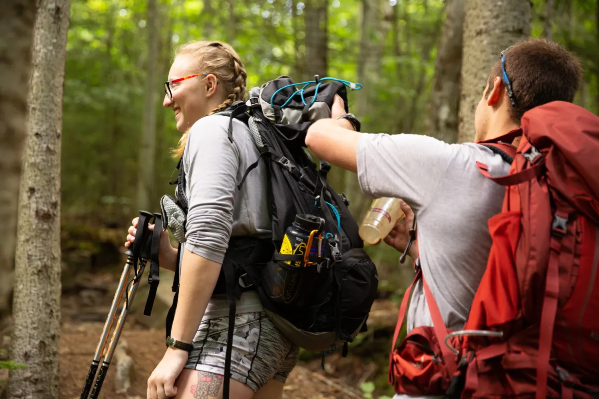 Two hikers picking up trash.
