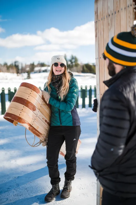 A woman holds a toboggan. 