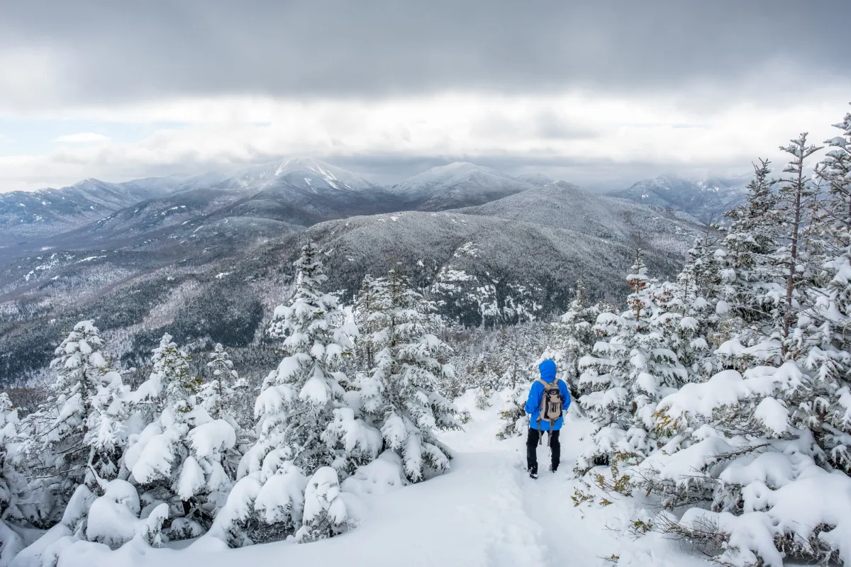 A person winter hiking at the top of a snowy summit.