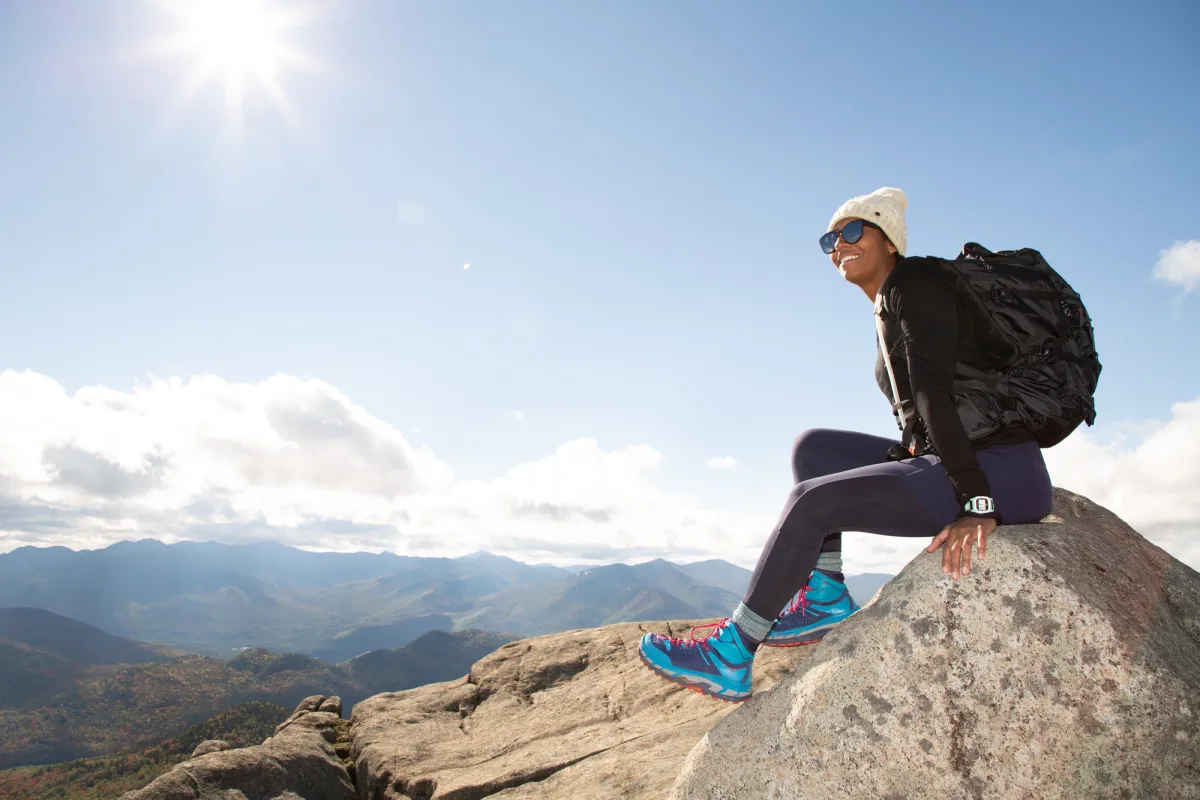 a woman sits on a rocky mountain top in fall.