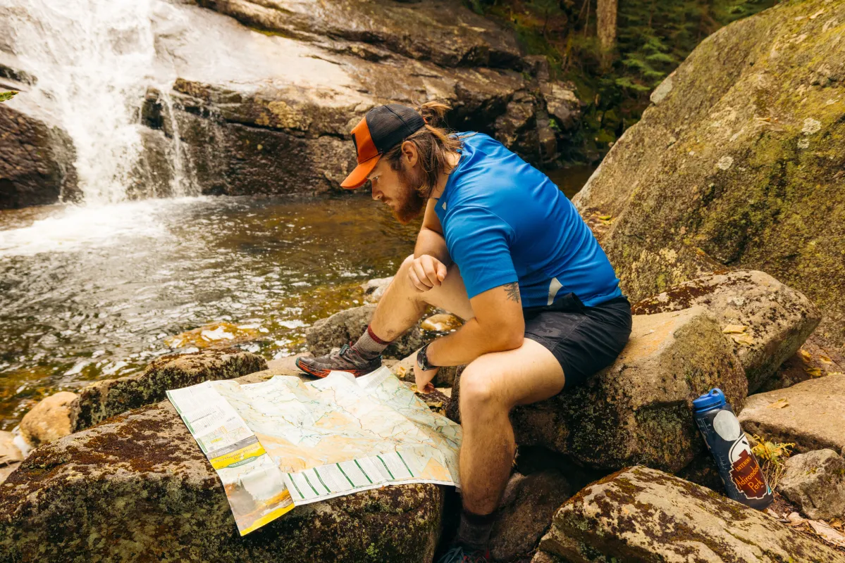 A hiker looking at a map in front of Wanika Falls.