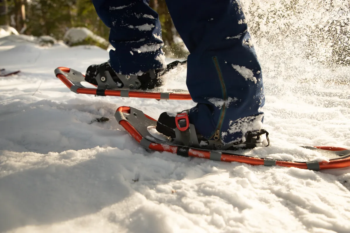 A close up photo of person snowshoeing through a snowy trail.