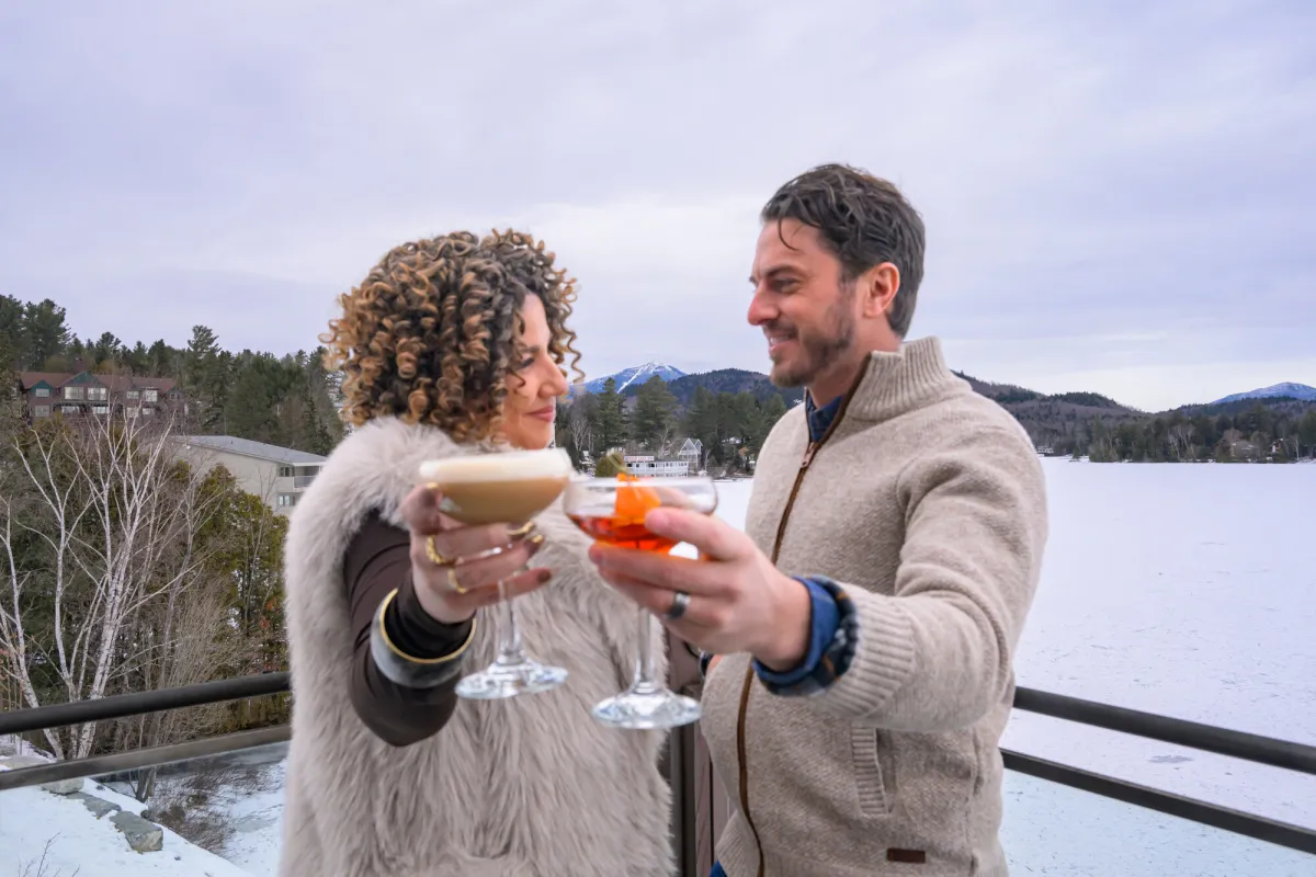 A couple raising their glasses on an outdoor patio in the winter.