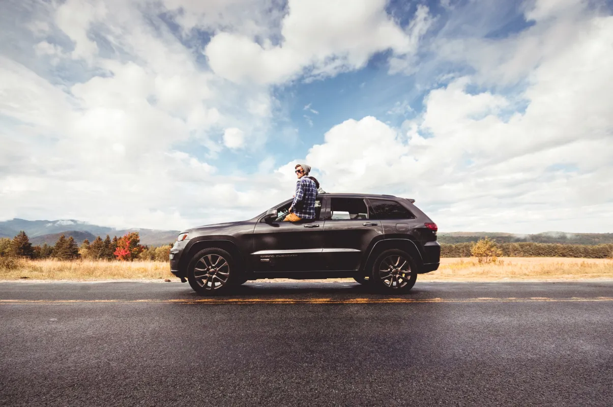 A man sits outside the drivers window of a Jeep Grand Charokee. 