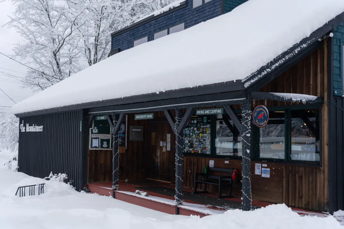 The exterior of a modern building with snow covering the roof and ground beyond the porch.