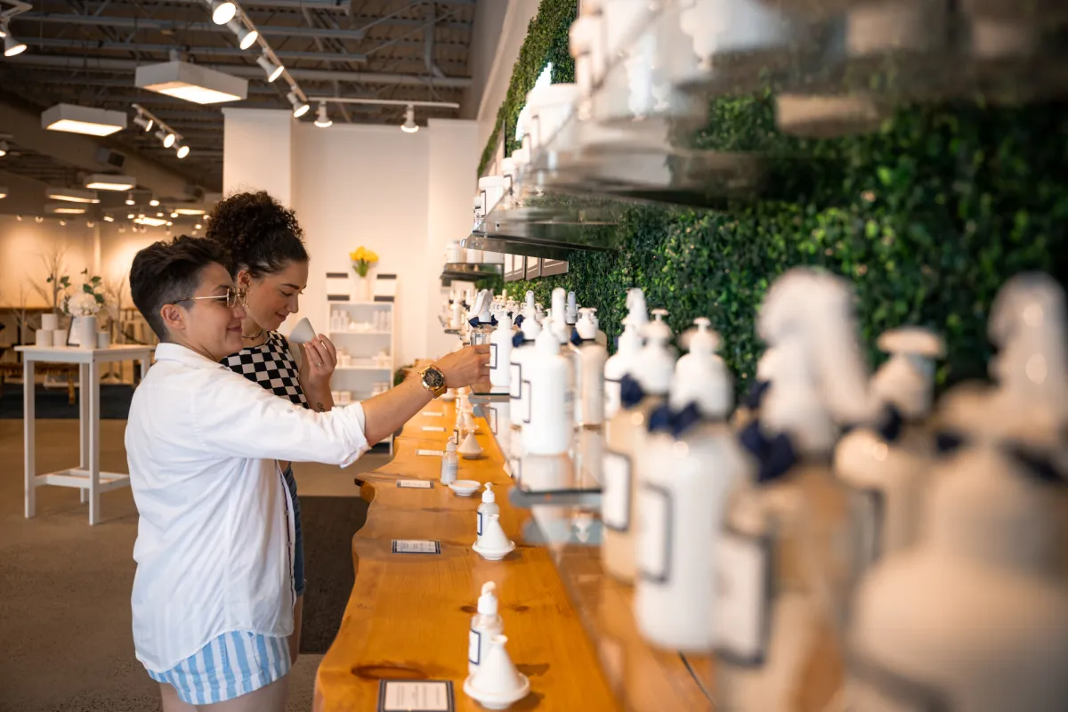 Two women test lotion while shopping in boutique shop