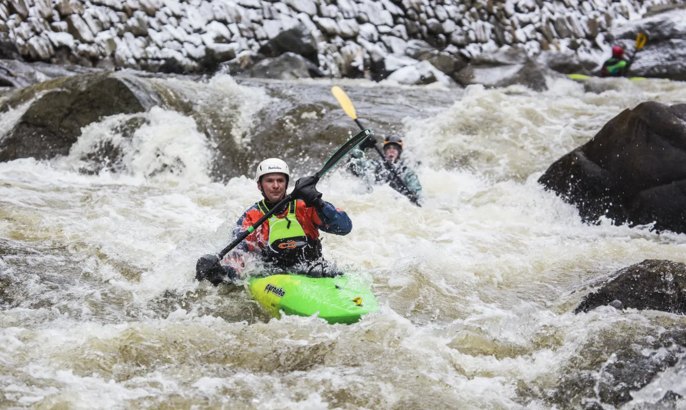 Two people whitewater kayaking down a river.