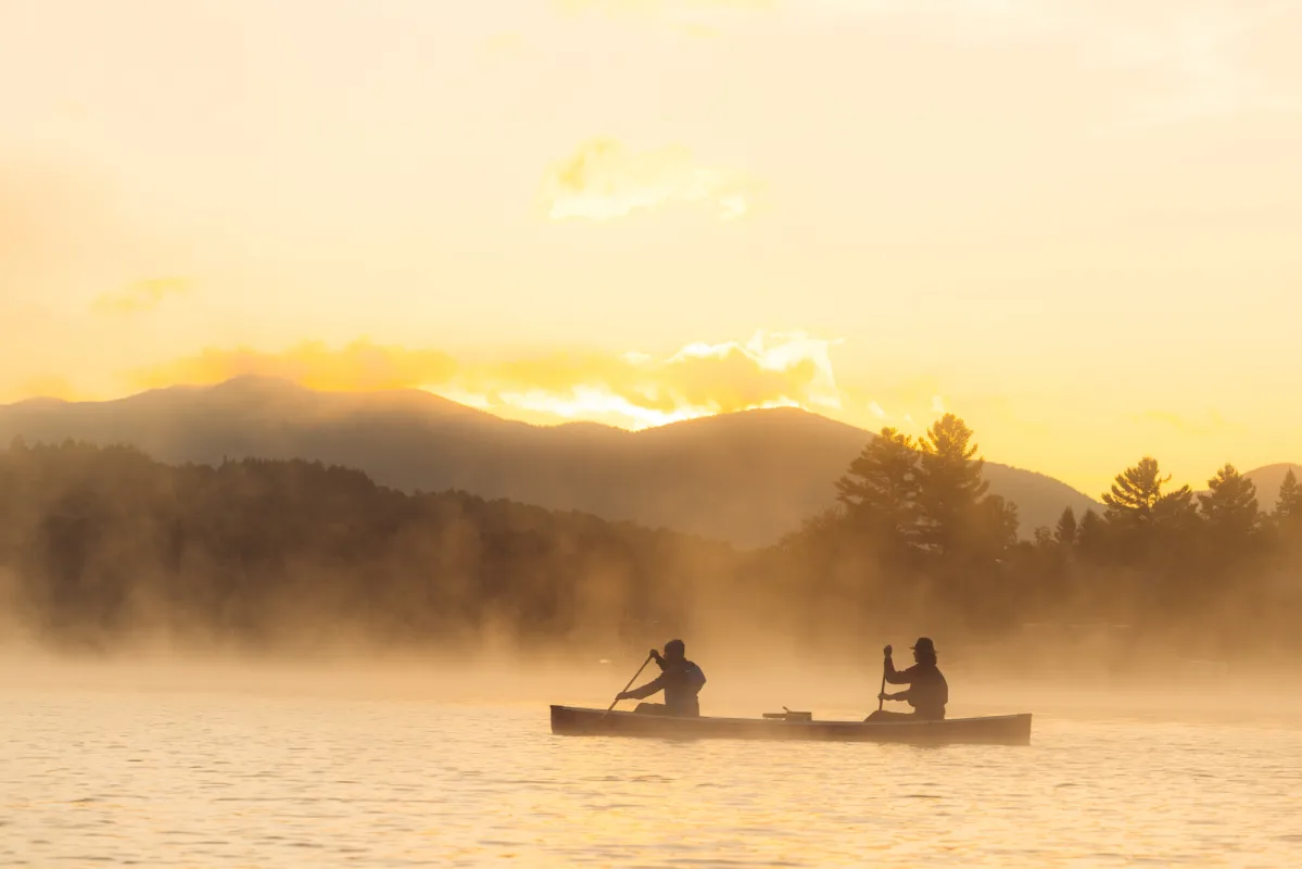 Two people in a canoe during sunrise