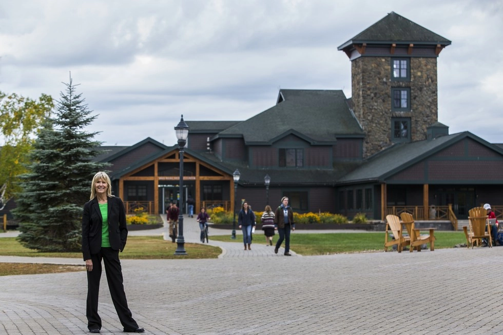 A woman poses with a college in the background. 