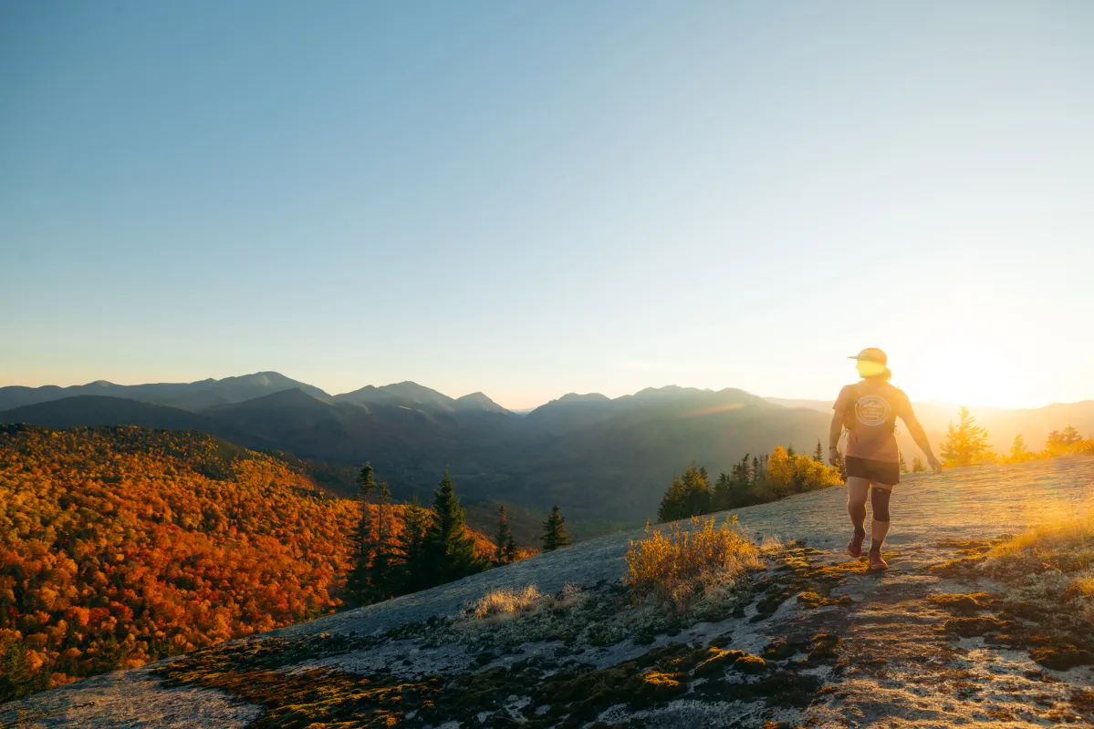 A man walks on a mountain top in the fall. 