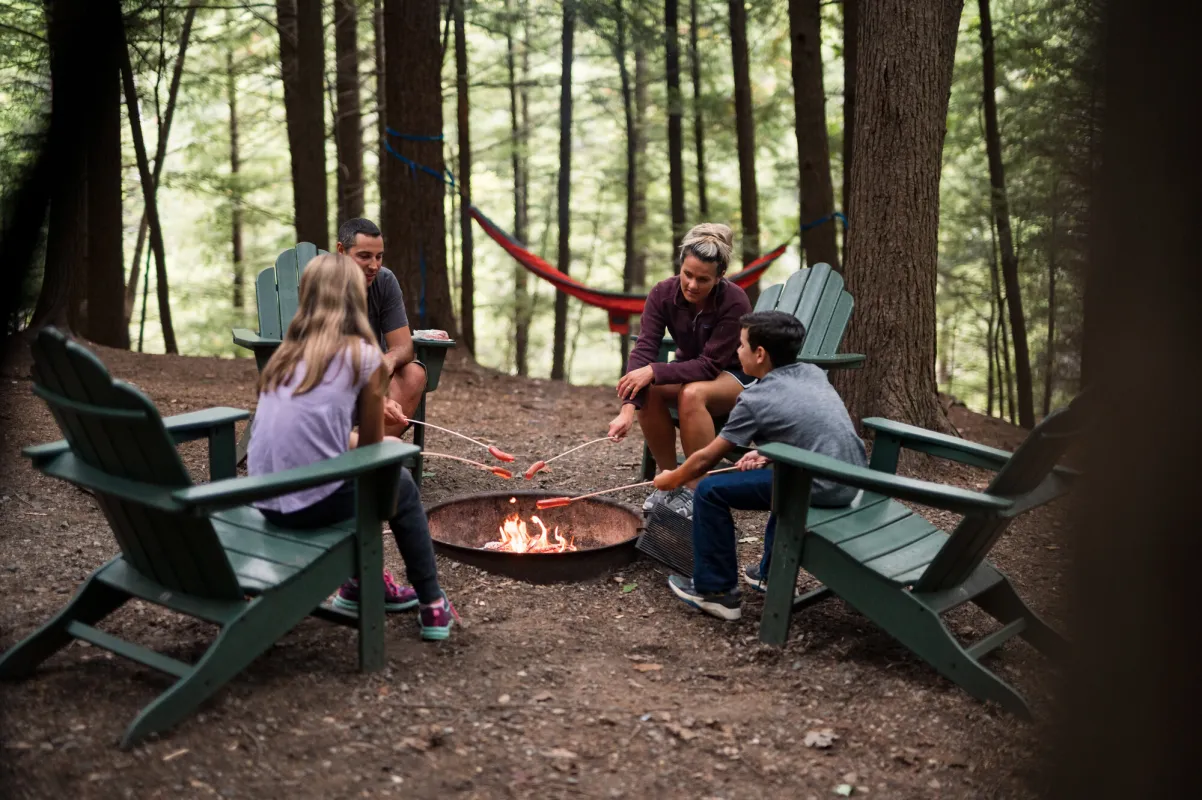A family around the campfire in Adirondack chairs.