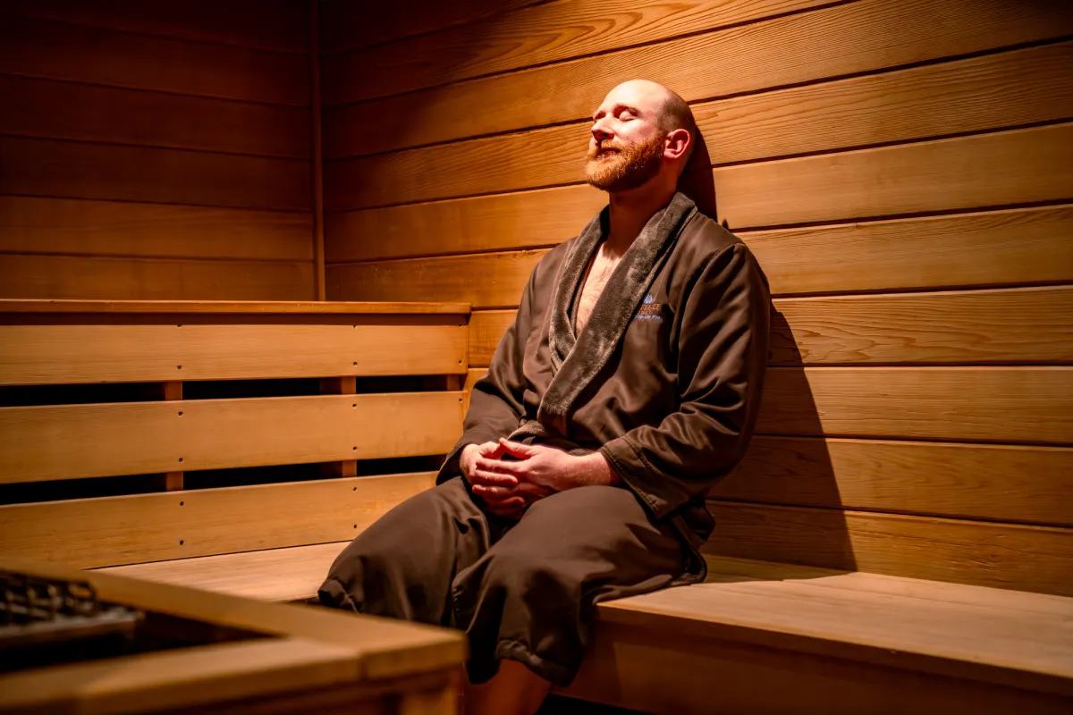 A man relaxes in a robe in a sauna. 