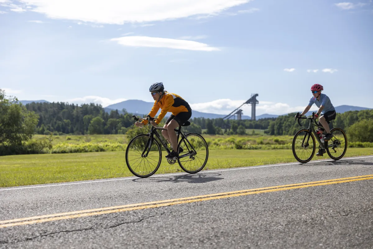 A group of cyclists on the road in front of the Lake Placid Ski Jumps.