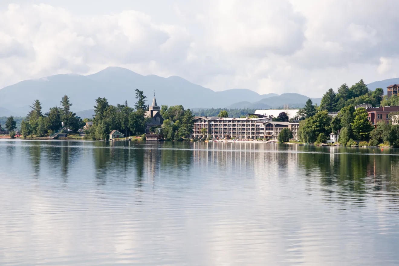 A hotel on clear water with mountains in the background. 