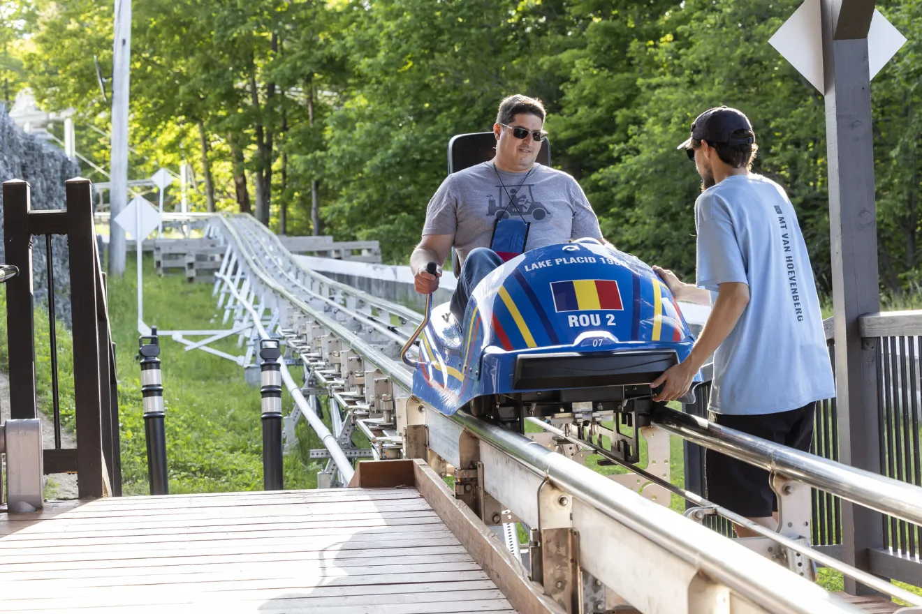 A man sits in a mountain coaster cart. 