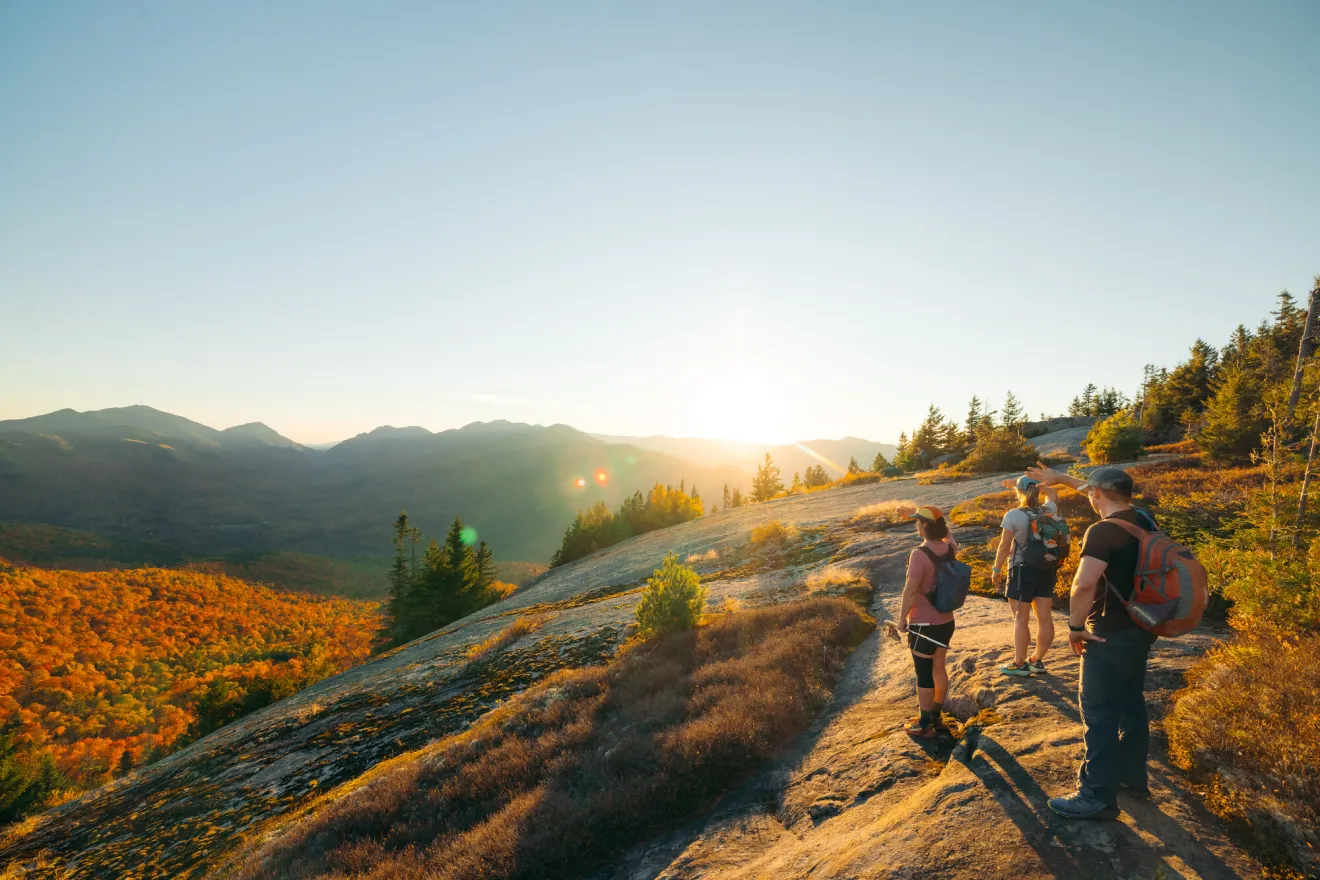 A group of hikers look out from a mountain top in fall.