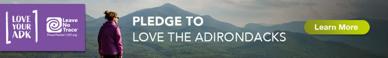 Banner ad for LoveYourAdk.com showing a woman on a mountain top staring at the view in front of her