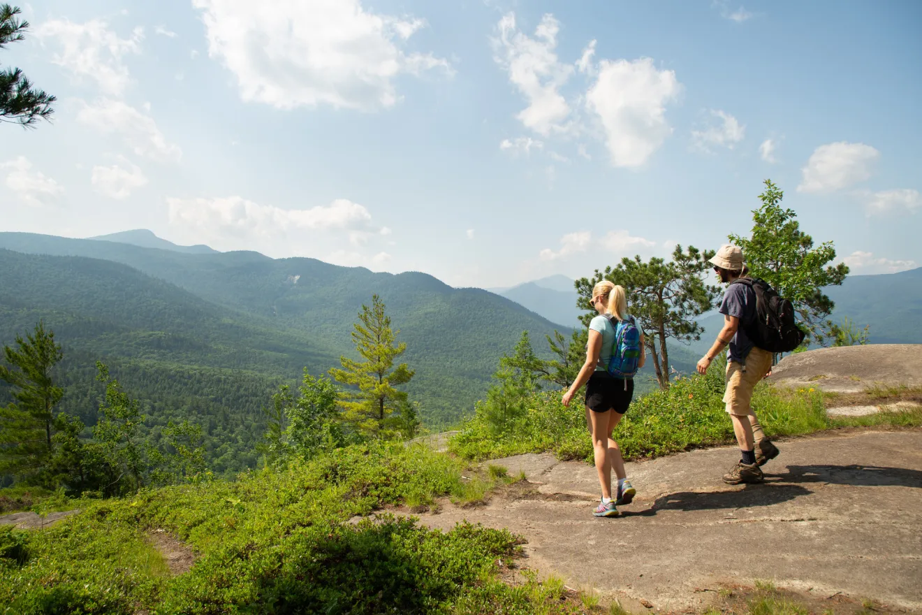 Two people walking around the summit of Baxter Mountain in the summer.